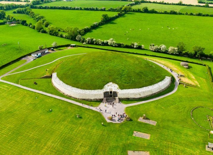 Aerial shot of Newgrange, Co Meath, with green fields in the background.