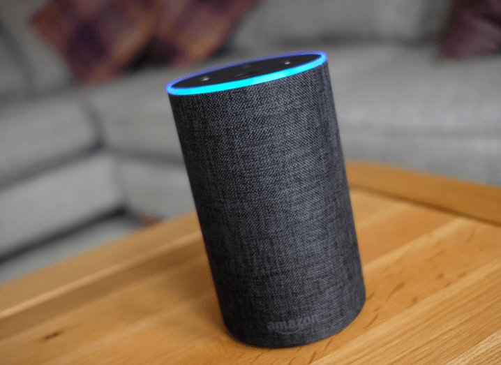 An Amazon Echo on a coffee table in front of a sofa.
