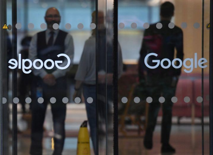 Looking through the Google-branded glass doors of a building with people going to and fro inside.