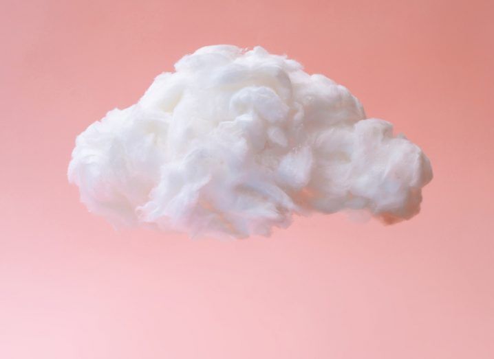 A single fluffy white cloud against a pastel coral background.