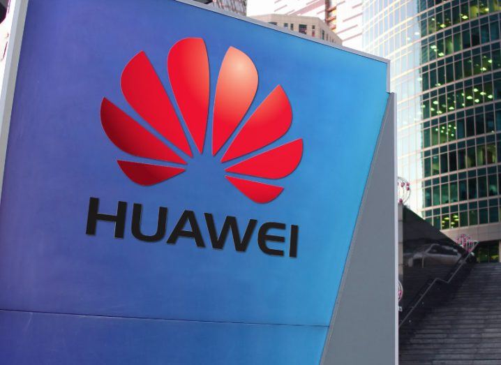 Red Huawei logo on a blue street sign.