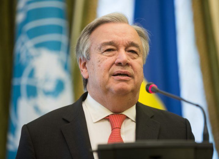António Guterres speaking at a podium with a UN flag seen behind him.