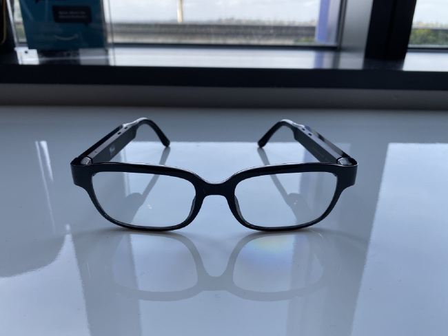 A pair of smart glasses with black frames pictured on a clean surface.