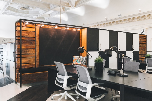 An open spacious room with a black desk and two office chairs seated at it