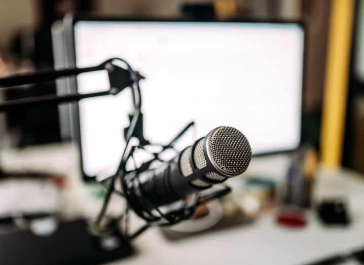 A home studio recording set-up with a microphone on an adjustable stand and an iMac set up in the background.