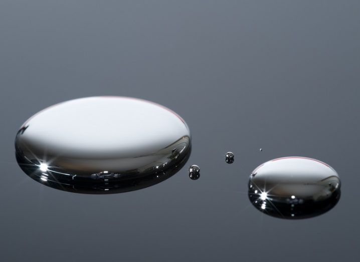 Two small puddles of liquid metal on a glass surface.