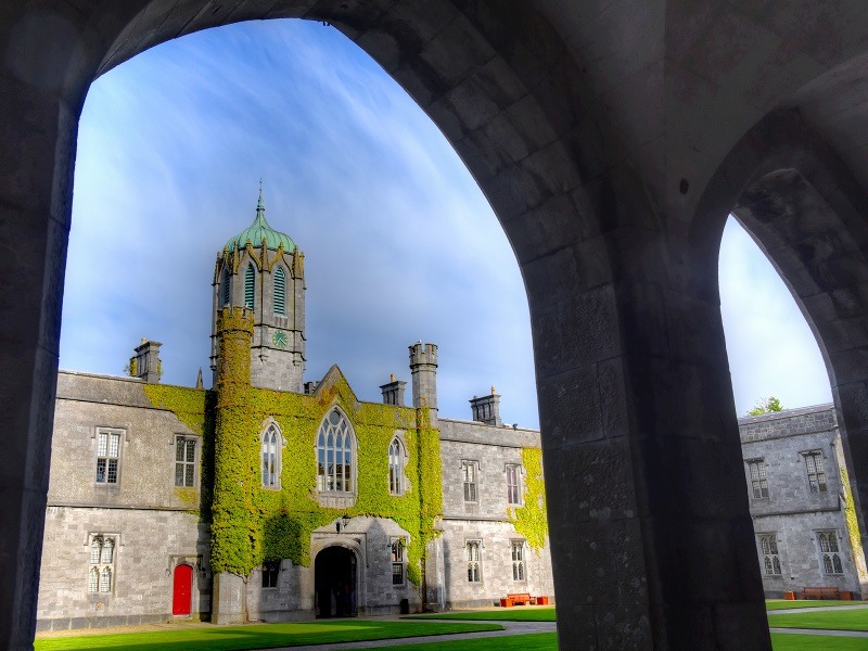 Shot from underneath an arch at NUI Galway against a blue sky.