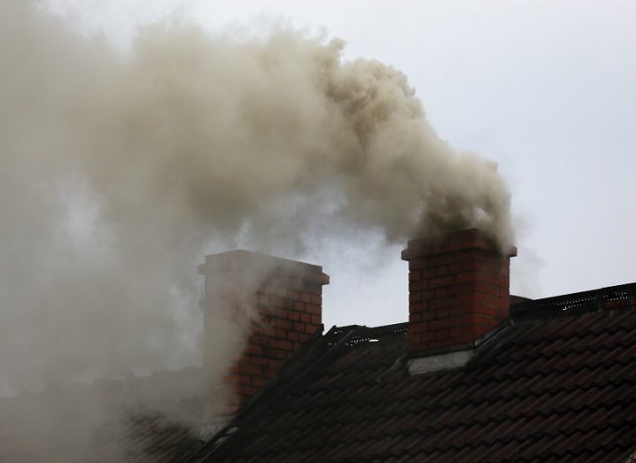 Brown smoke billowing out of a house's chimney.