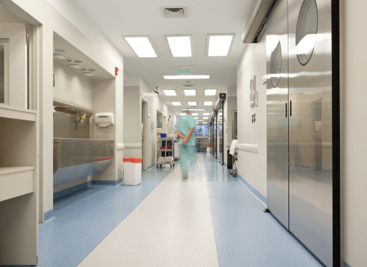 A doctor wearing scrubs walking down the corridor of a hospital.