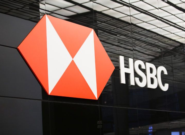 View of red and white HSBC Logo and company name on black glass office facade.