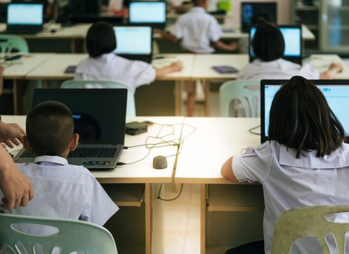 Children in a classroom sitting at desks with laptop computers.