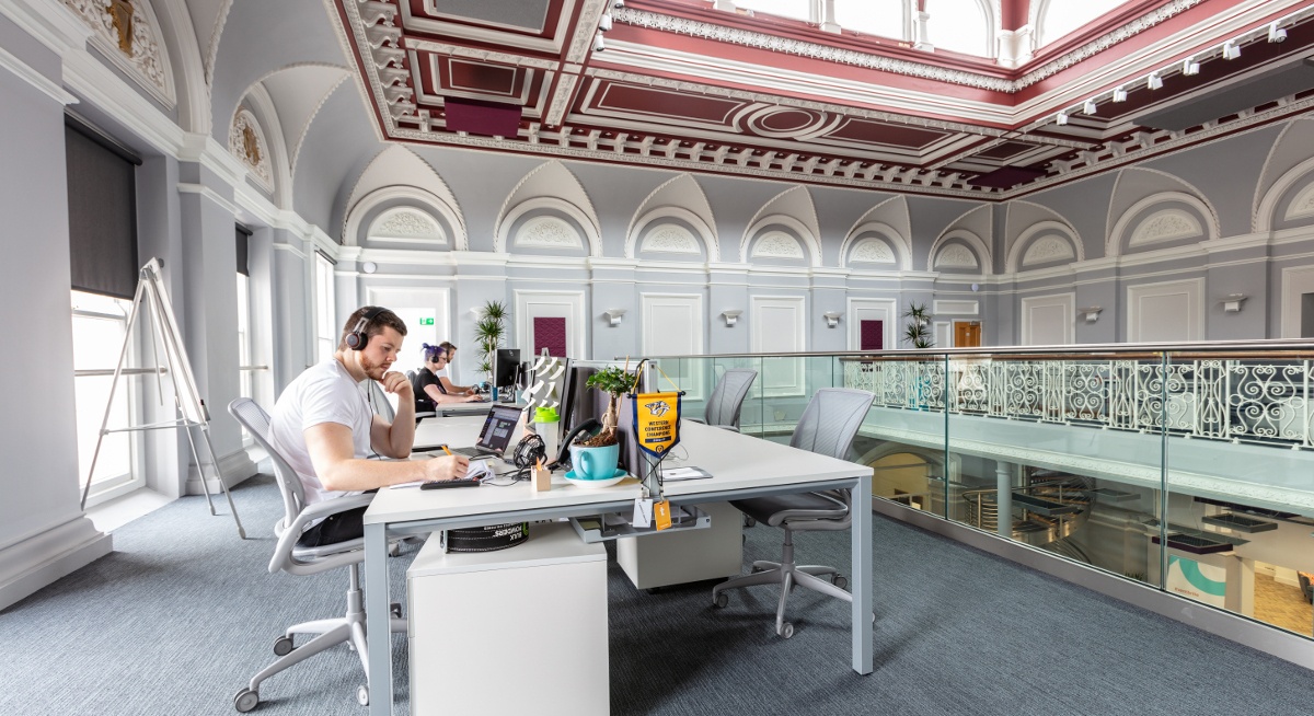 A man is working at a desk on his computer inside a contemporary, spacious and bright office at Eventbrite, Cork.