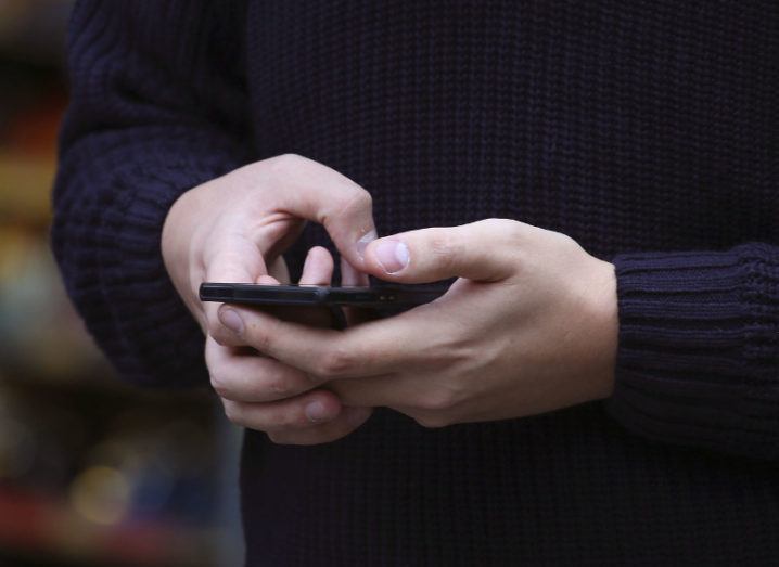 View of person in dark sweater holding phone in hand.