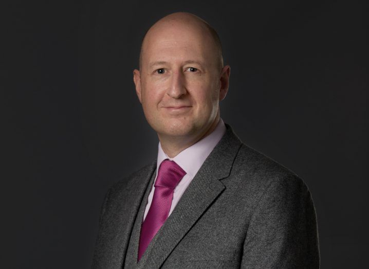 View of bald man in business attire wearing a pink tie.