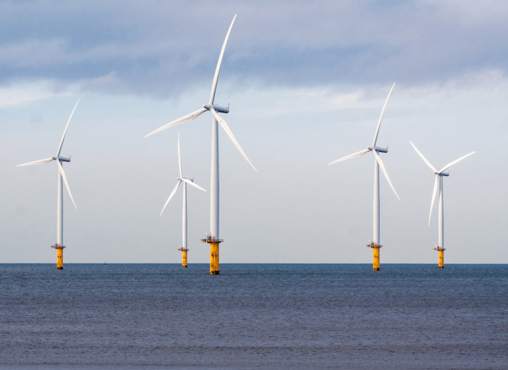 Wind turbines on a sea under a cloudy sky.