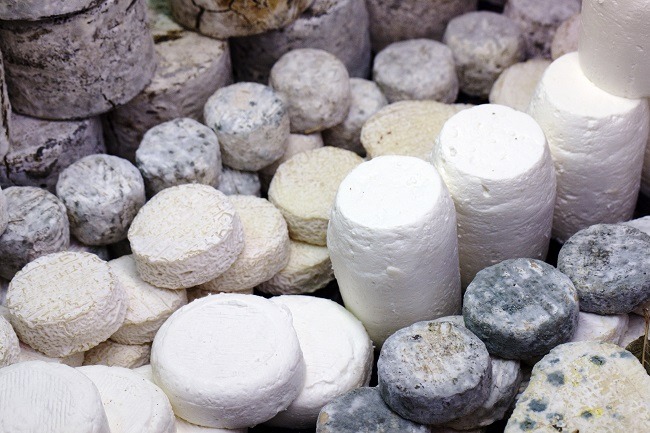 Stacks of various French cheeses coloured white, grey and black.