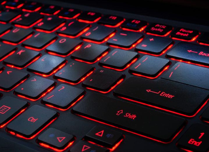 View of black keyboard keys backlit with red bright light.