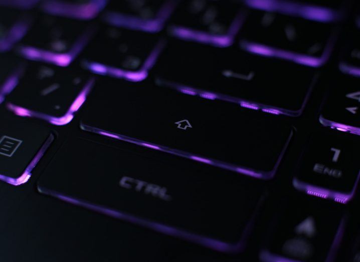 View of black laptop keyboard backlit with purple light.