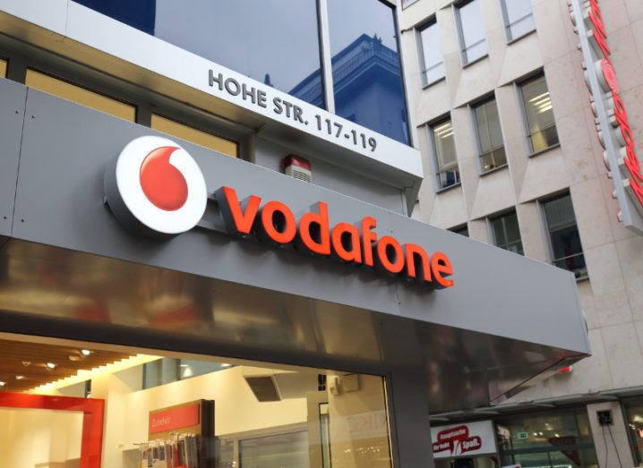View of vodafone logo in red and white on front of modern building.