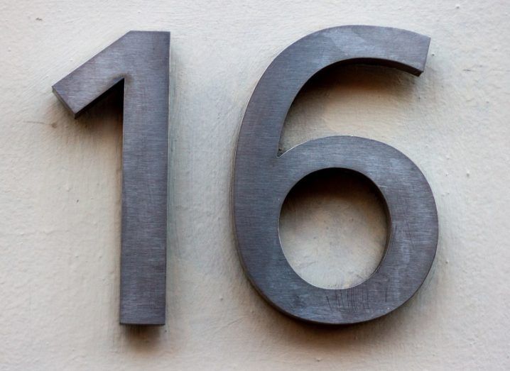 The number 16 in grey metal letters on a white wall.