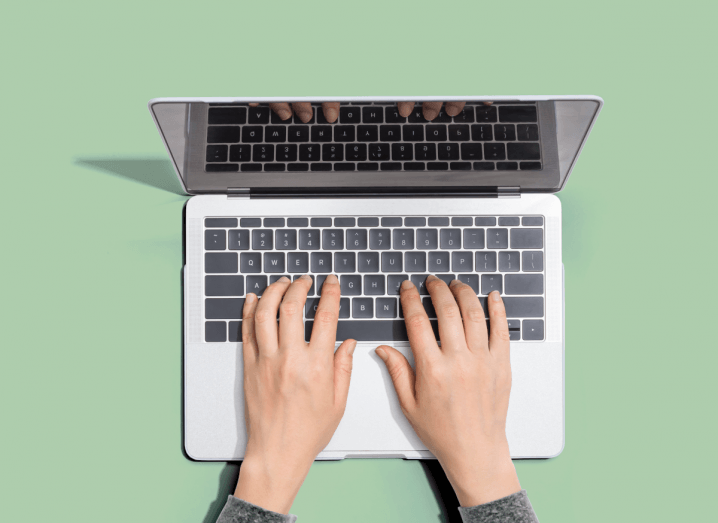 Pale green background with hands typing on a laptop symbolising the future of work.