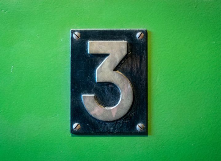 A metal door sign bearing the number three on a bright green background.