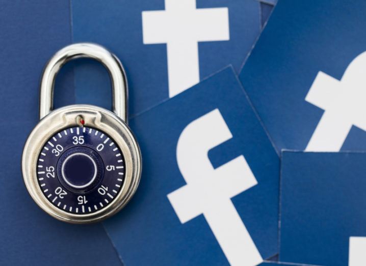 A pile of blue paper Facebook logos with a combination padlock placed on top.