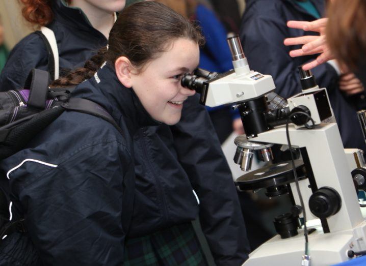 Student looking through a microscope at the BT Young Scientist and Technology Exhibition.