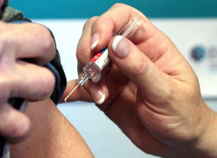 Doctor's hand injecting a patient with a vaccine using a syringe.
