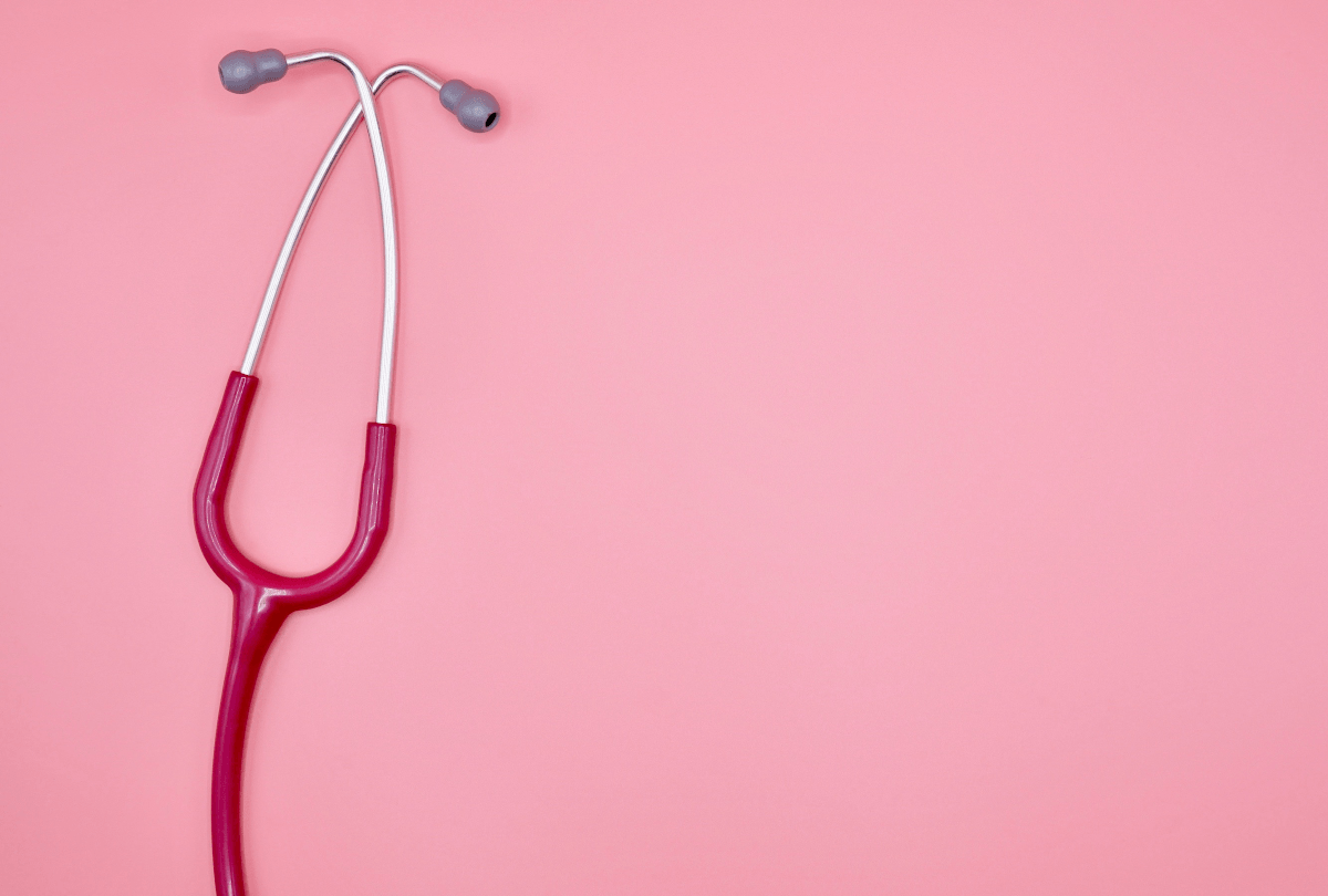A stethoscope with a red cord laid flat on a pink background.