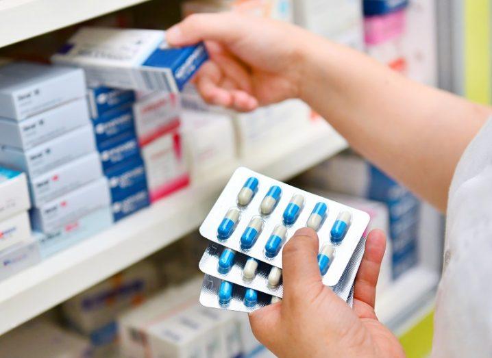 Pharmacist putting boxes of antibiotics on a pharmacy shelf.