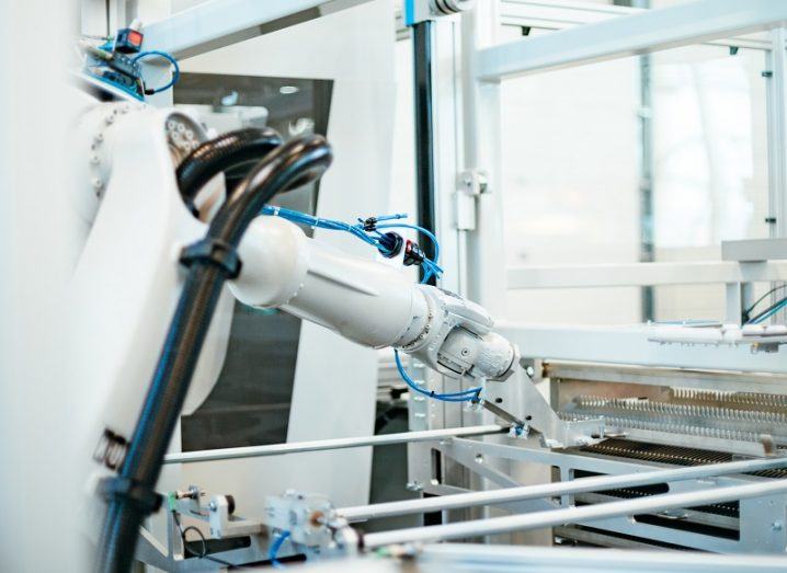 A white robotic arm in a research facility working on a production line.