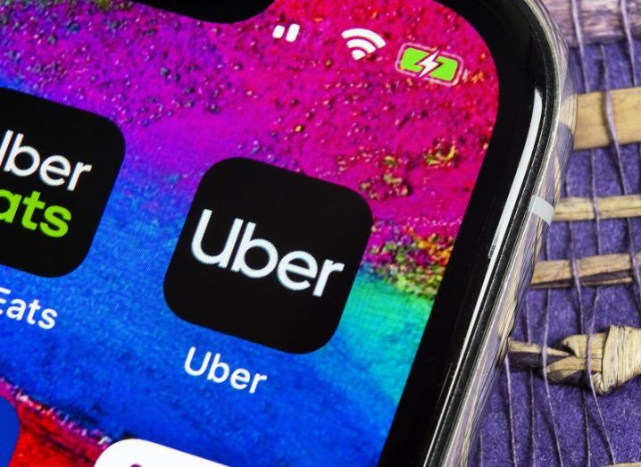 Close-up of a phone showing the Uber and Uber Eats apps on a bright, multicoloured screen background.