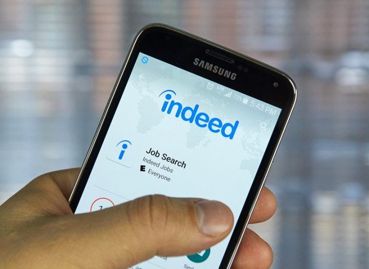 Hand holding a phone with the Indeed app on screen.