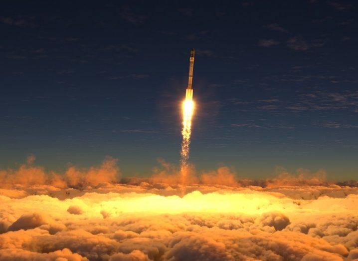 Rocket taking off into space covering clouds below in an orange glow.