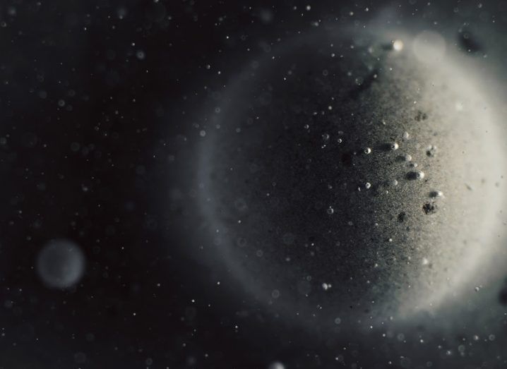 Abstract image of grey bubbles representing the moon and a smaller moon against a black background.