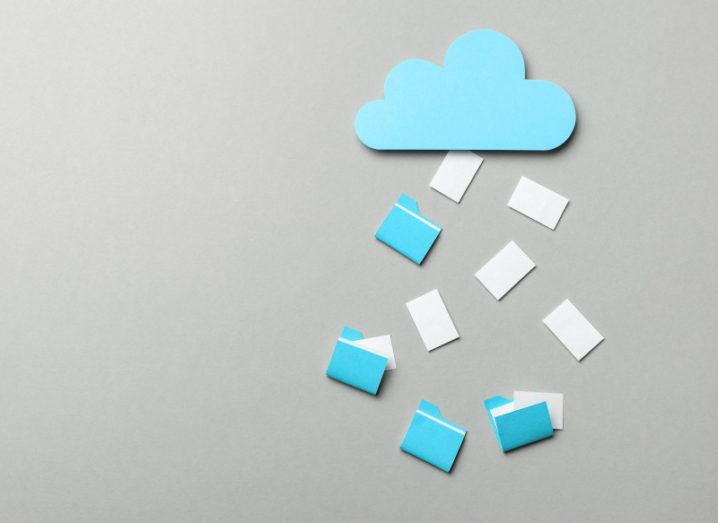 A blue paper cloud with documents and files falling out of it, all set against a grey background.