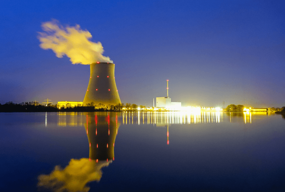 A nuclear power plant in front of a body of water at night.