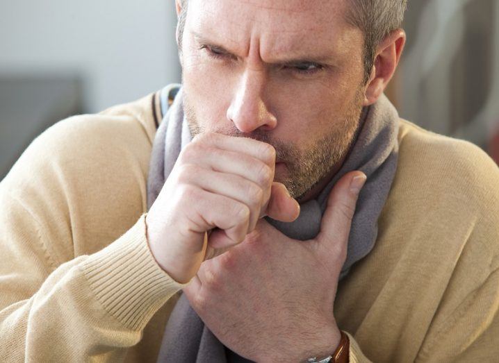 Man holding his hand in front of his face while coughing.