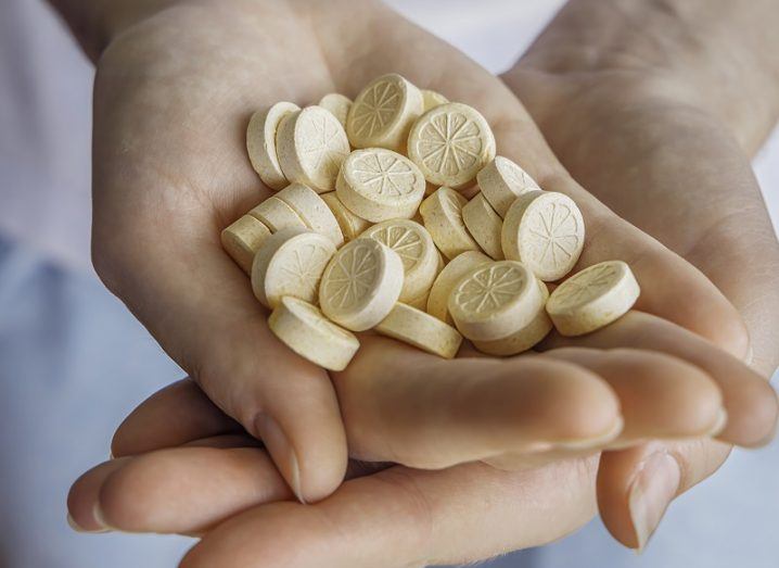 Pair of hands holding vitamin C tablets.