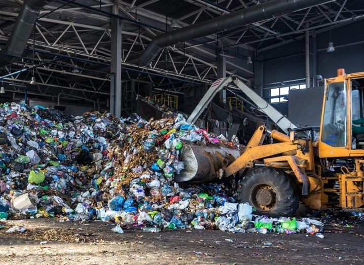 Digger truck scooping up a pile of hazardous waste in a warehouse.