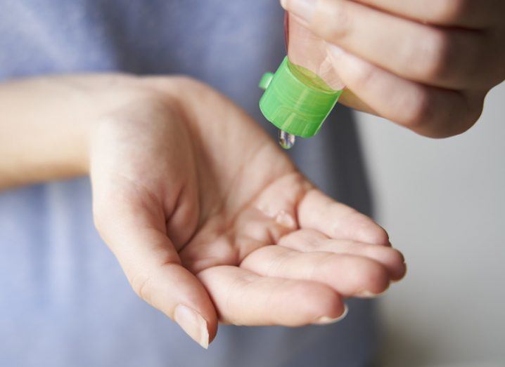 Close-up of a woman’s hands as she squeezes hand sanitiser from a small bottle.