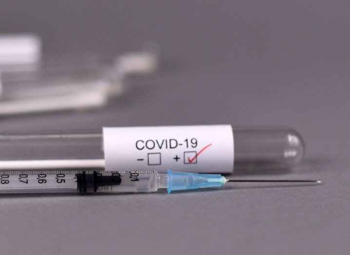 Syringe beside a test tube that has a label saying Covid-19.