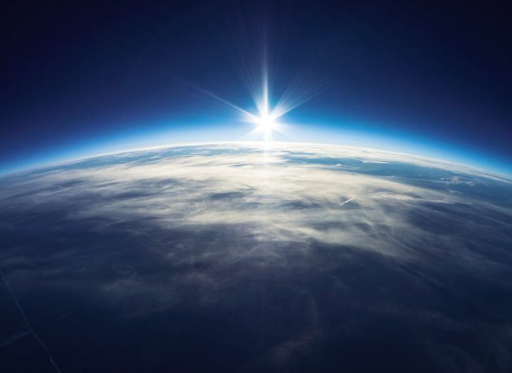 Render of the sun rising above the Earth, seen from orbit.