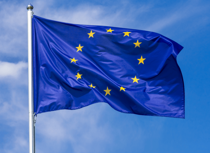 The EU flag waving in the wind against a blue sky.