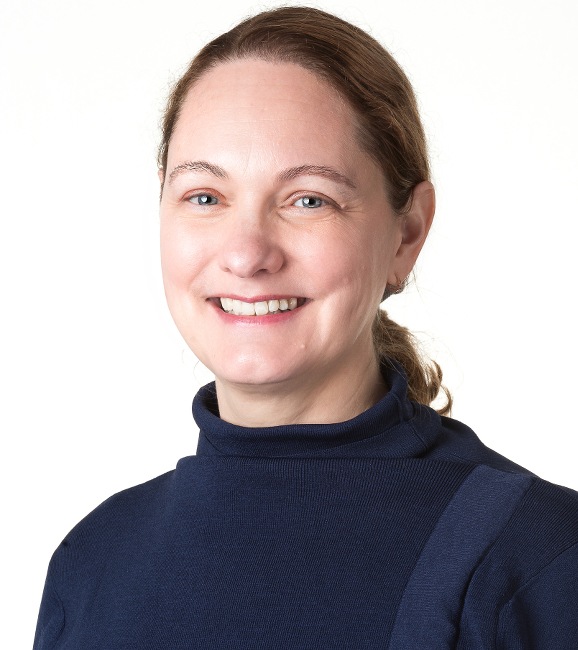 Headshot of a smiling woman in a navy turtleneck against a white background.