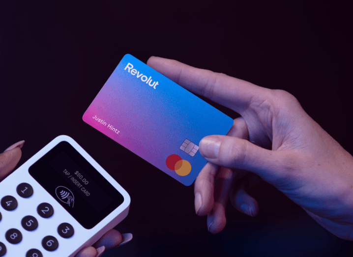 A person tapping their Revolut card on a contactless payment terminal.