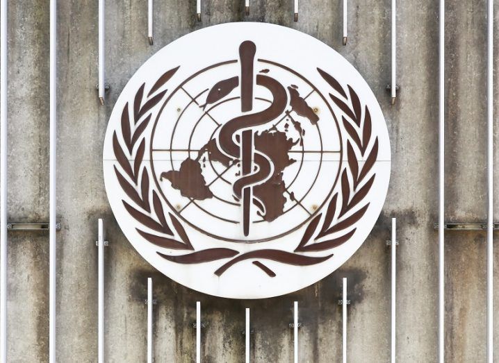 The World Health Organization logo on a concrete and steel wall.