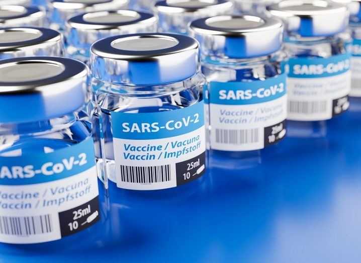 Concept of a row of coronavirus vaccine bottles on a blue surface.