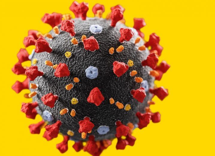 3D render of the coronavirus against a yellow background.